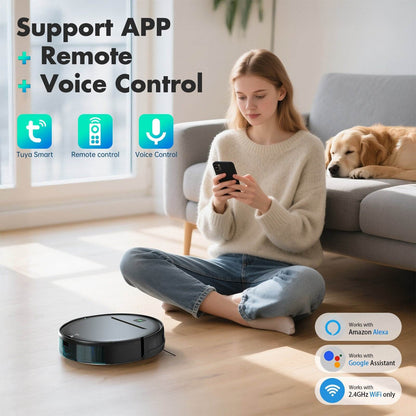 Woman using a smartphone with a robot vacuum cleaner on the floor, dog lying on a couch in the background.